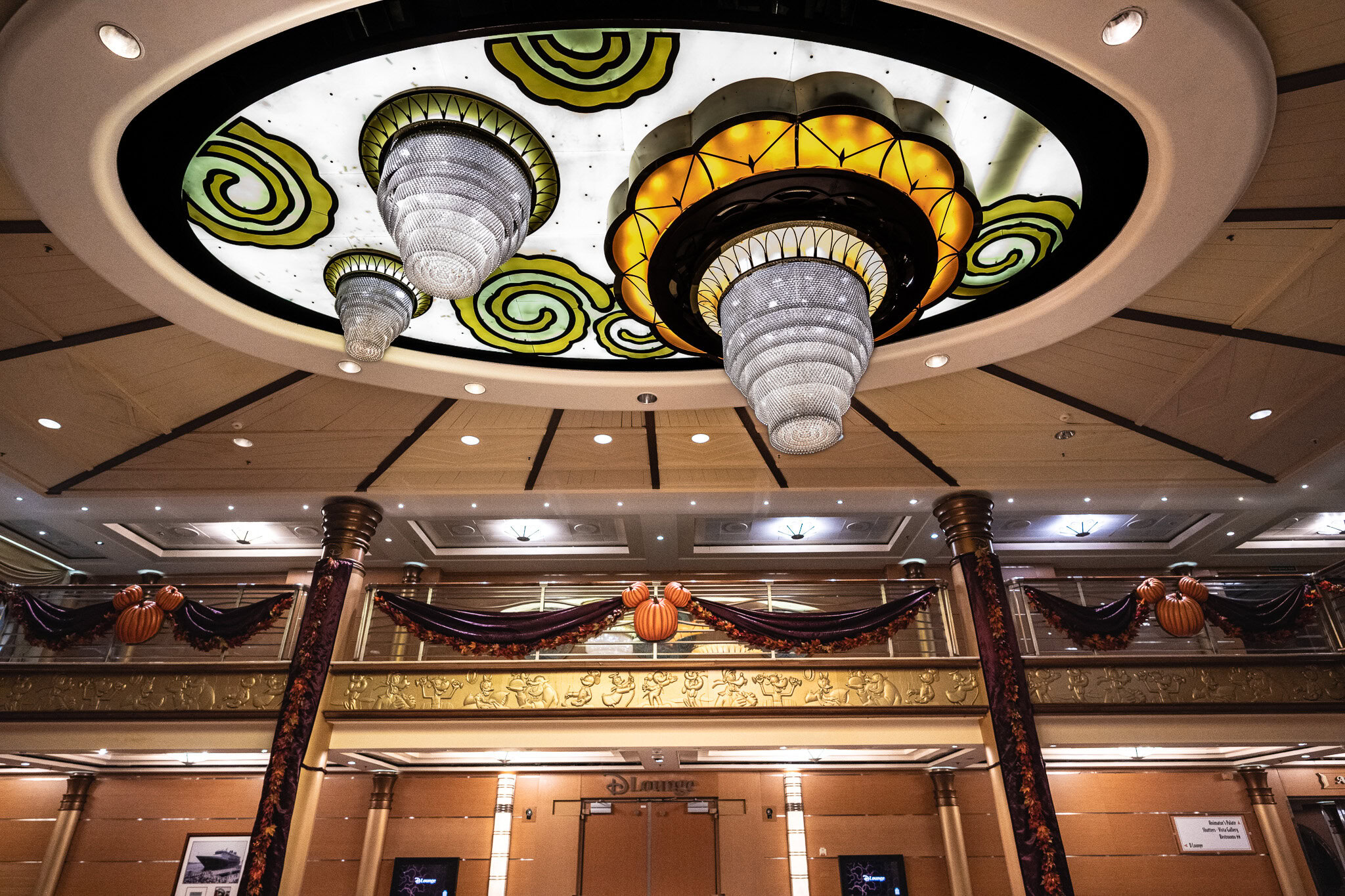 Disney Magic atrium ceiling chandeliers decorated with pumpkins and garlands for Halloween on the High Seas.