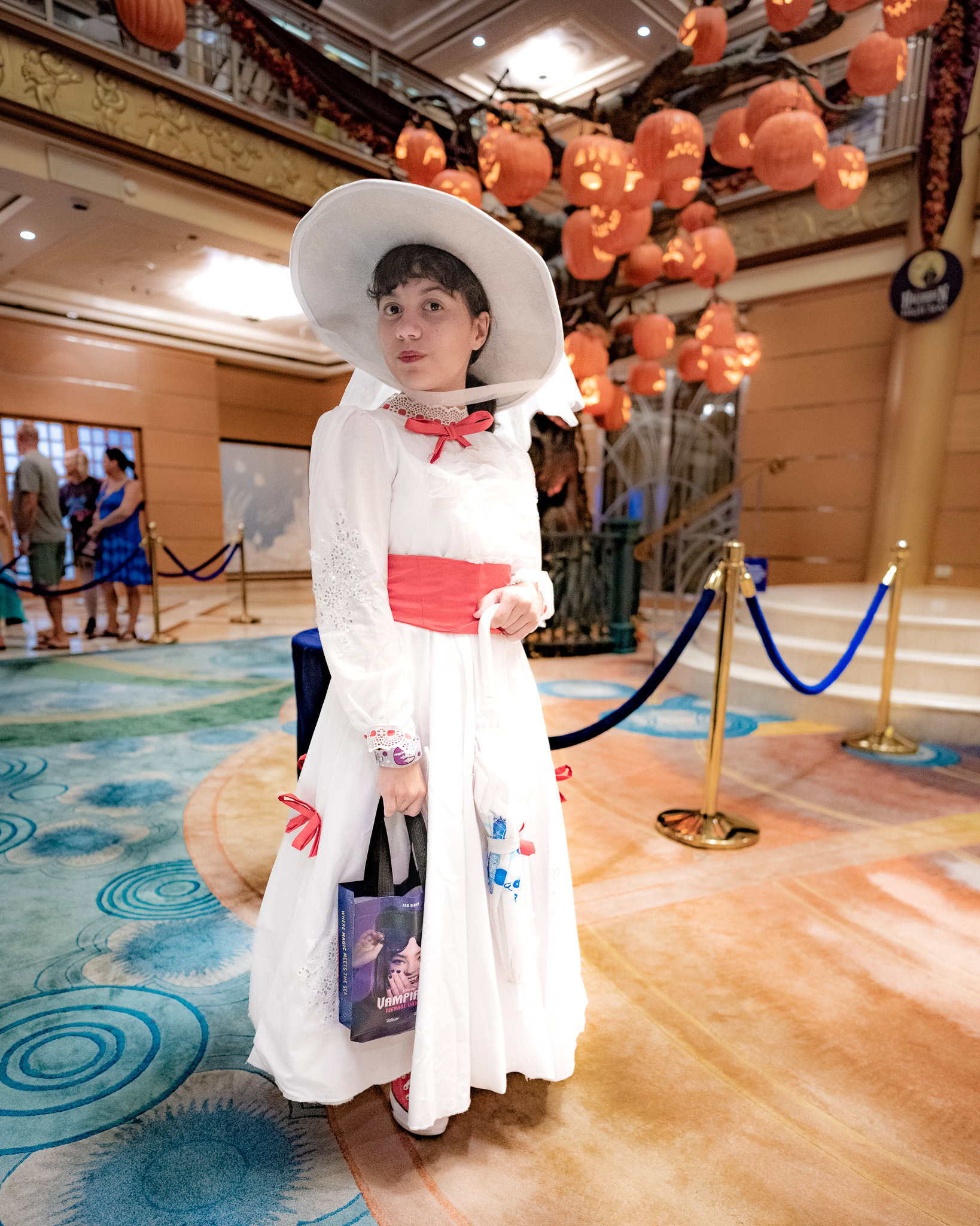 Daniela dressed as Mary Poppins posing in the Disney Magic atrium decorated for Halloween on the High Seas.