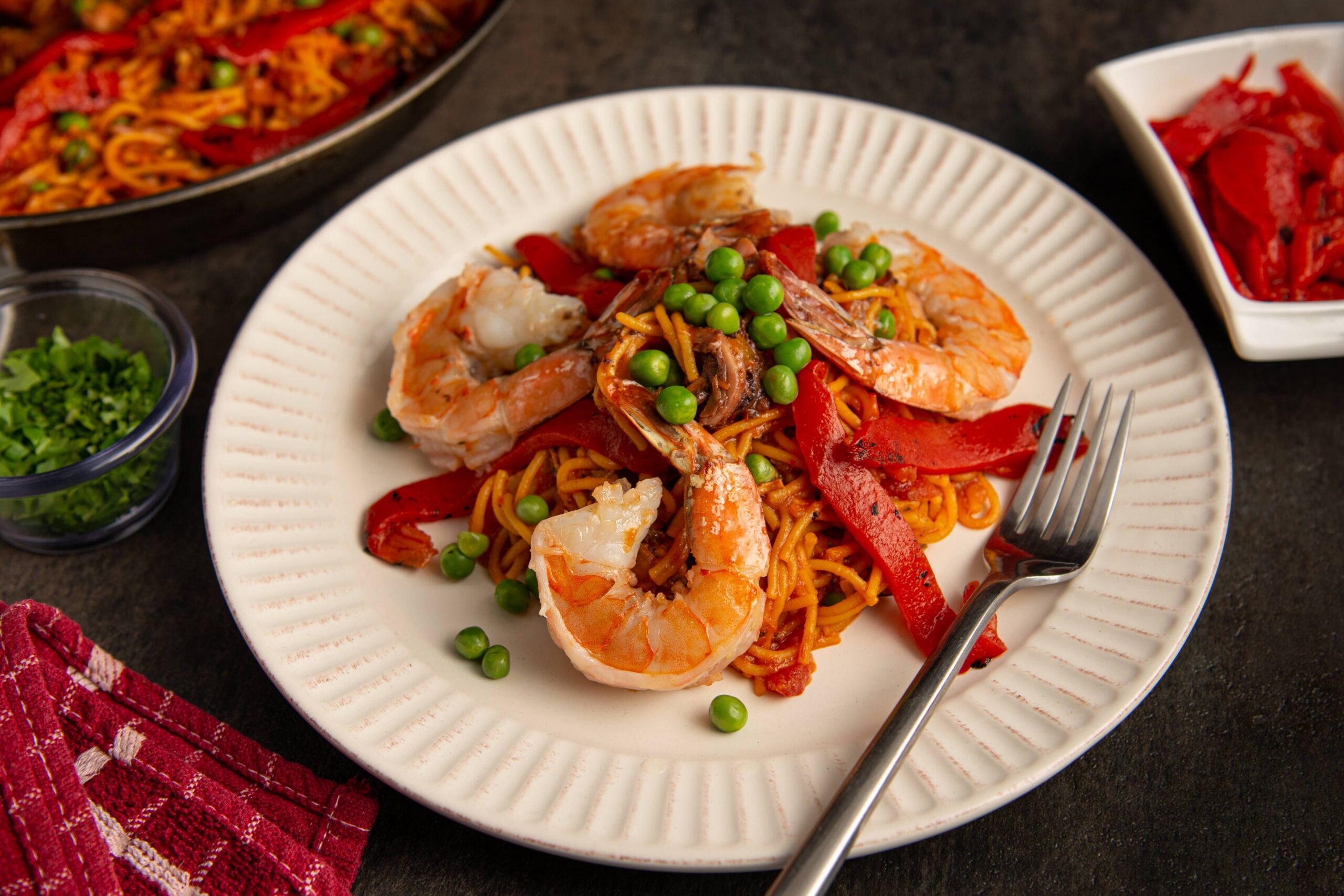 Fideuá de mariscos with shrimp, squid, peas and roasted peppers served on a white plate prepared by a private chef in Puerto Rico.