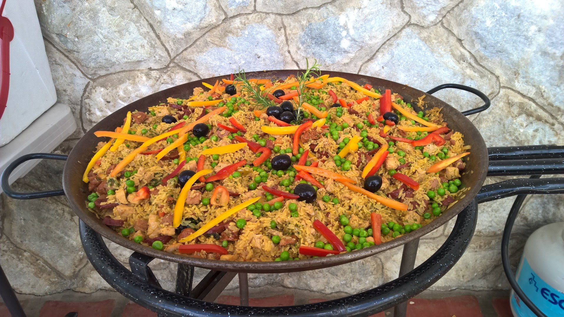 Large paella-style arroz dish with peppers, olives and peas prepared outdoors by a private chef in Puerto Rico.