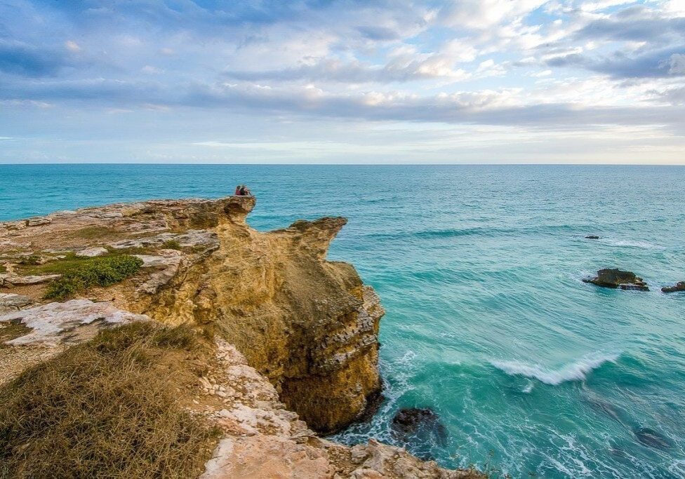 Rocky coastal cliffs at Cabo Rojo Lighthouse (El Faro), Puerto Rico overlooking turquoise ocean waters at sunset