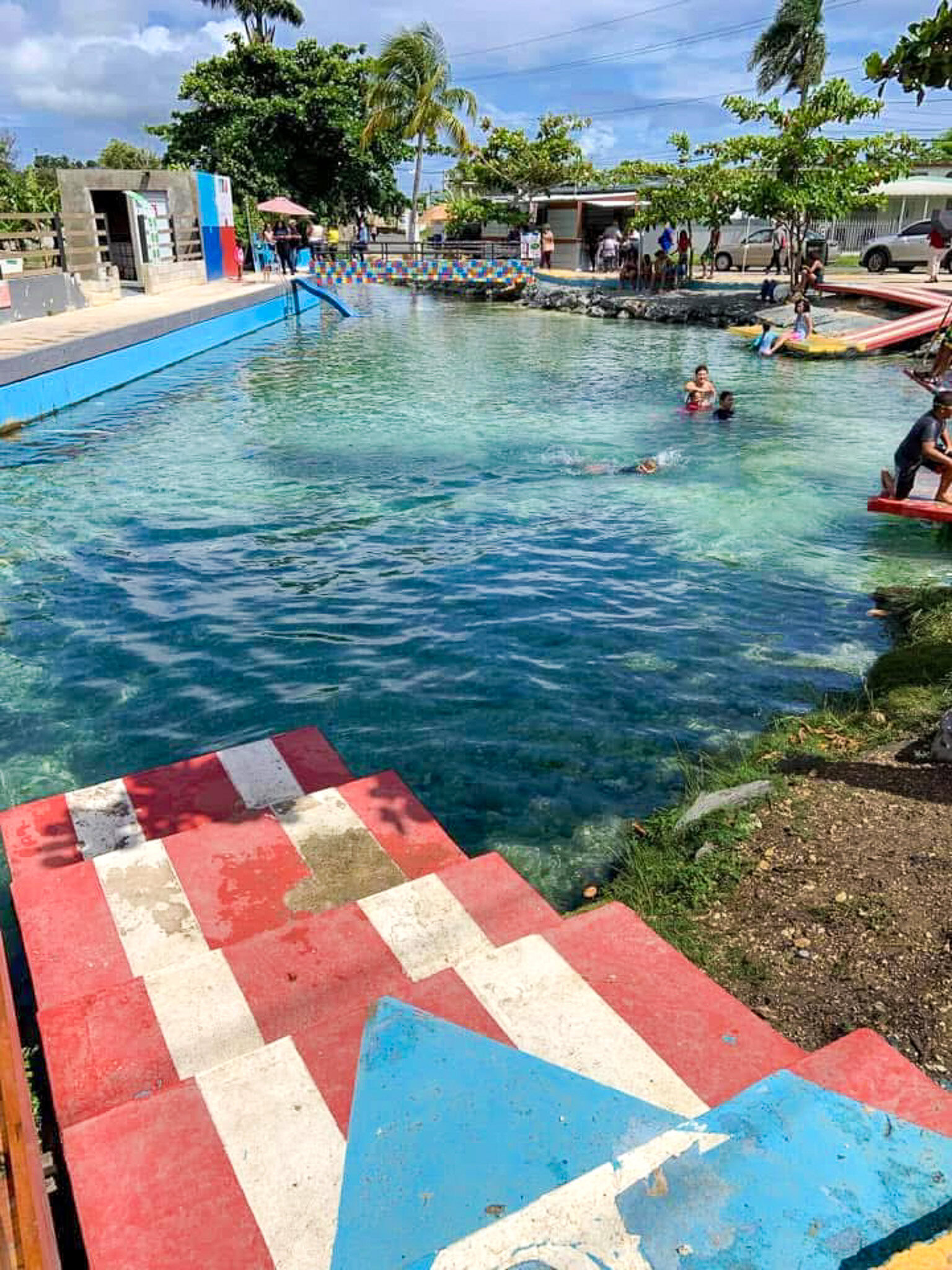 Ojo de Agua natural spring in Vega Baja Puerto Rico with clear water and Puerto Rican flag steps.