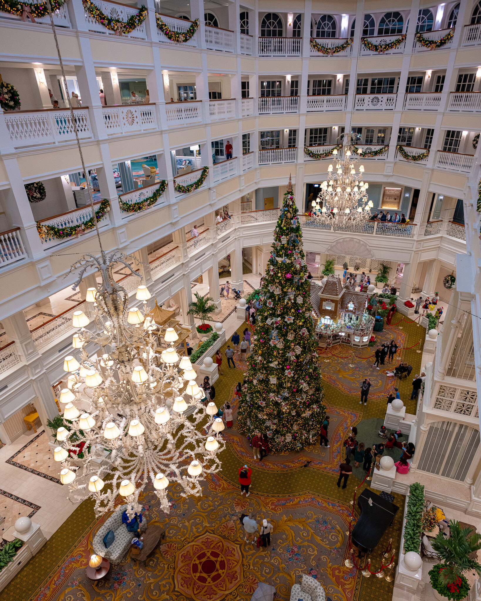 Massive decorated Christmas tree and gingerbread house in the Grand Floridian Resort lobby during the holiday season.