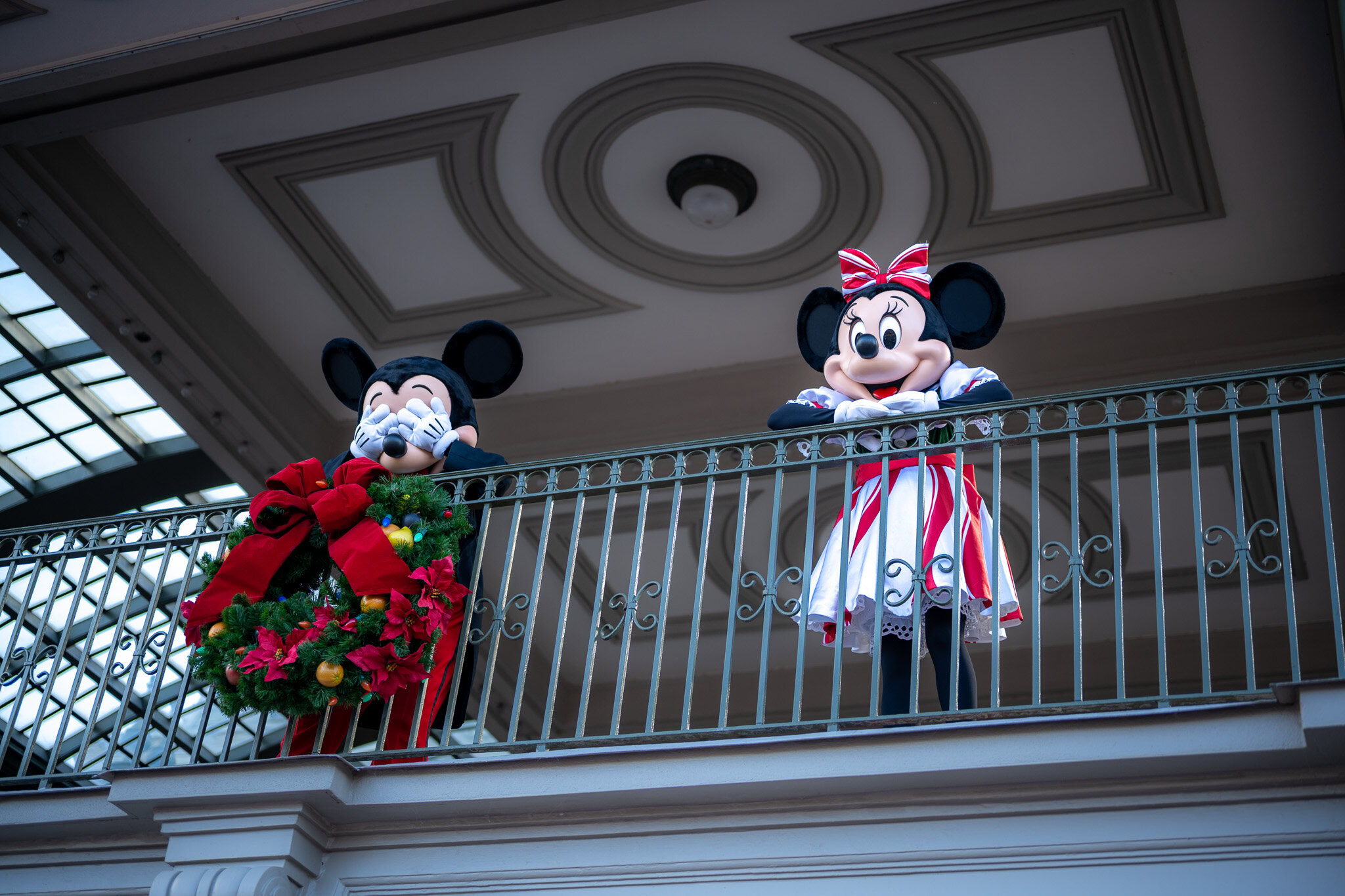 Mickey and Minnie Greet Guests at Magic Kingdom During the Holidays Mickey and Minnie in holiday outfits at the Magic Kingdom entrance decorated with garlands.