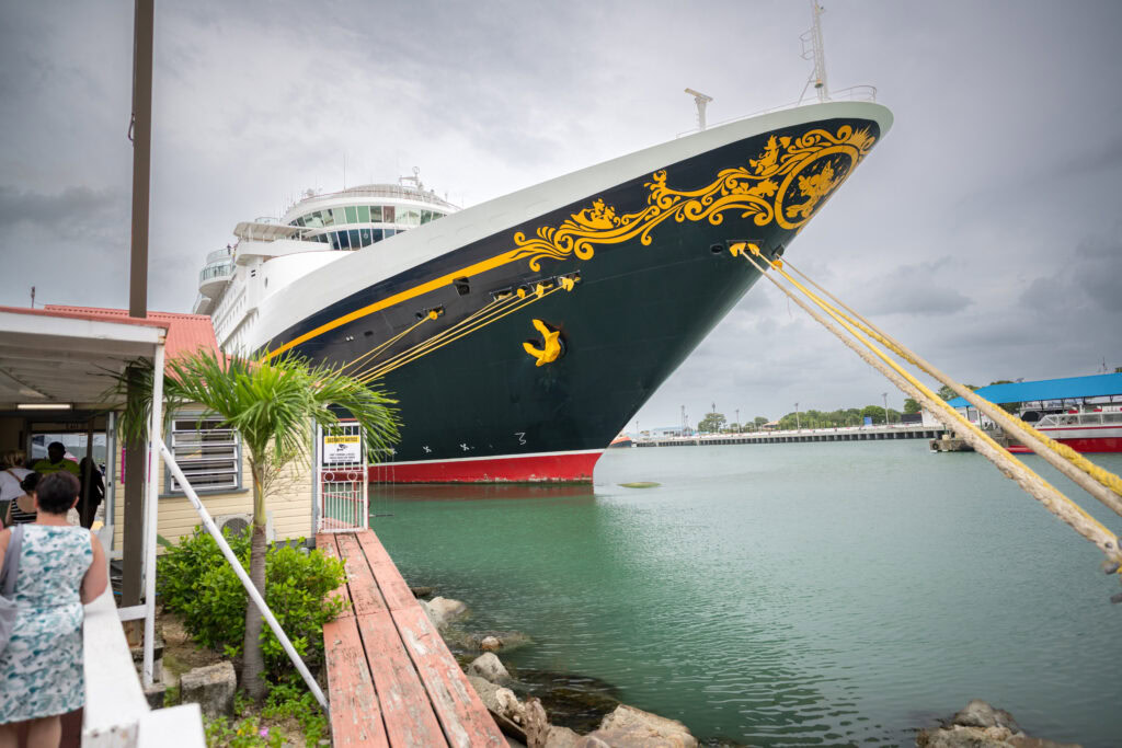 Disney Magic cruise ship docked at Antigua port with cloudy sky backdrop.