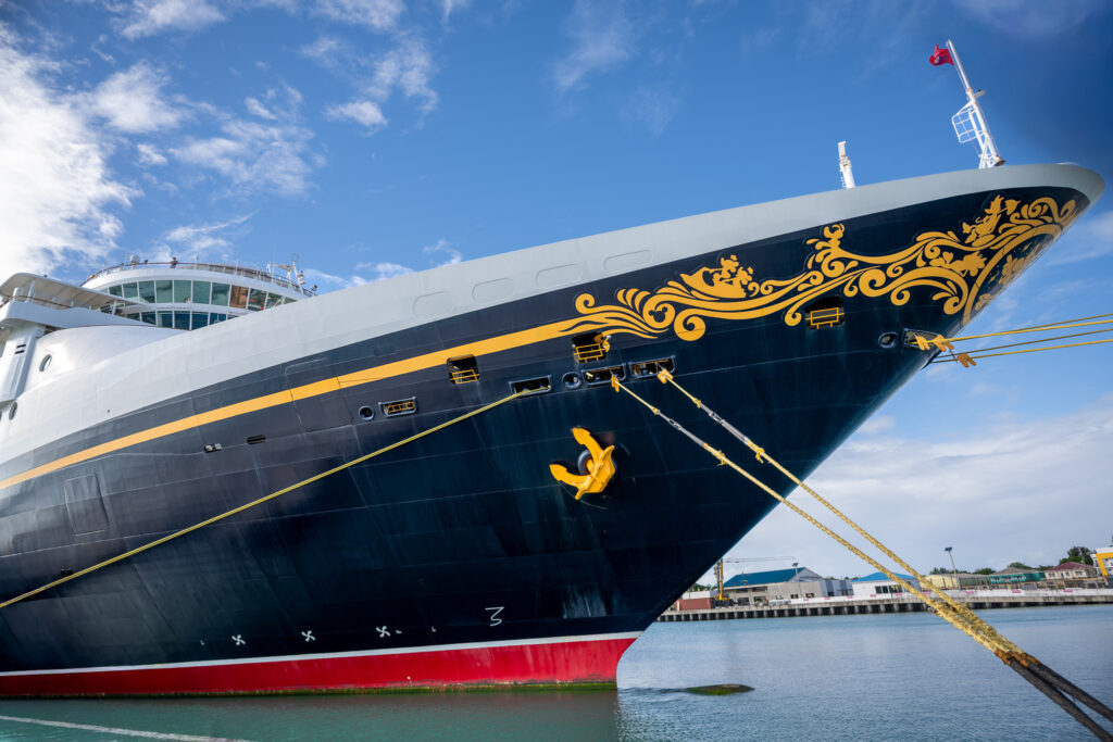 Disney Magic cruise ship docked in St. John&rsquo;s, Antigua, photographed from a low angle with clear blue skies.
