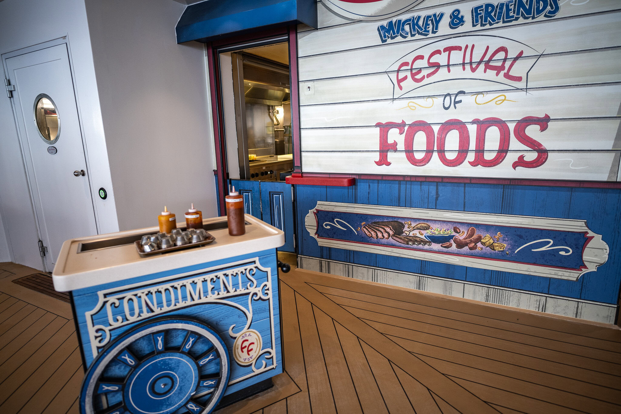 Disney Wish Festival of Foods condiment station with colorful signage and sauce bottles on the pool deck.