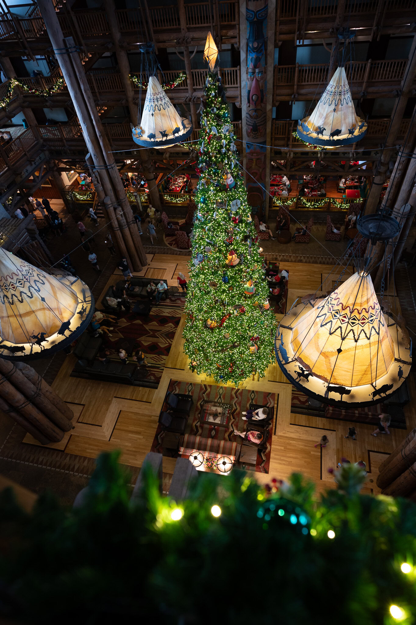 Holiday view of Disney’s Wilderness Lodge lobby with Christmas tree and rustic lantern lighting