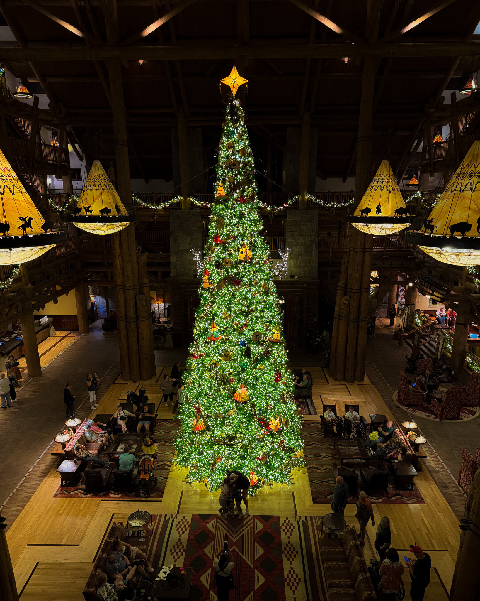 Christmas tree at Disney’s Wilderness Lodge lobby surrounded by guests and holiday decorations