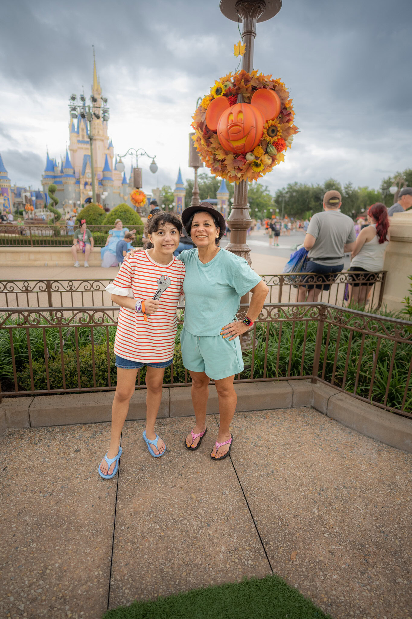 Guests posing in front of Cinderella Castle and Mickey pumpkin wreath at Magic Kingdom