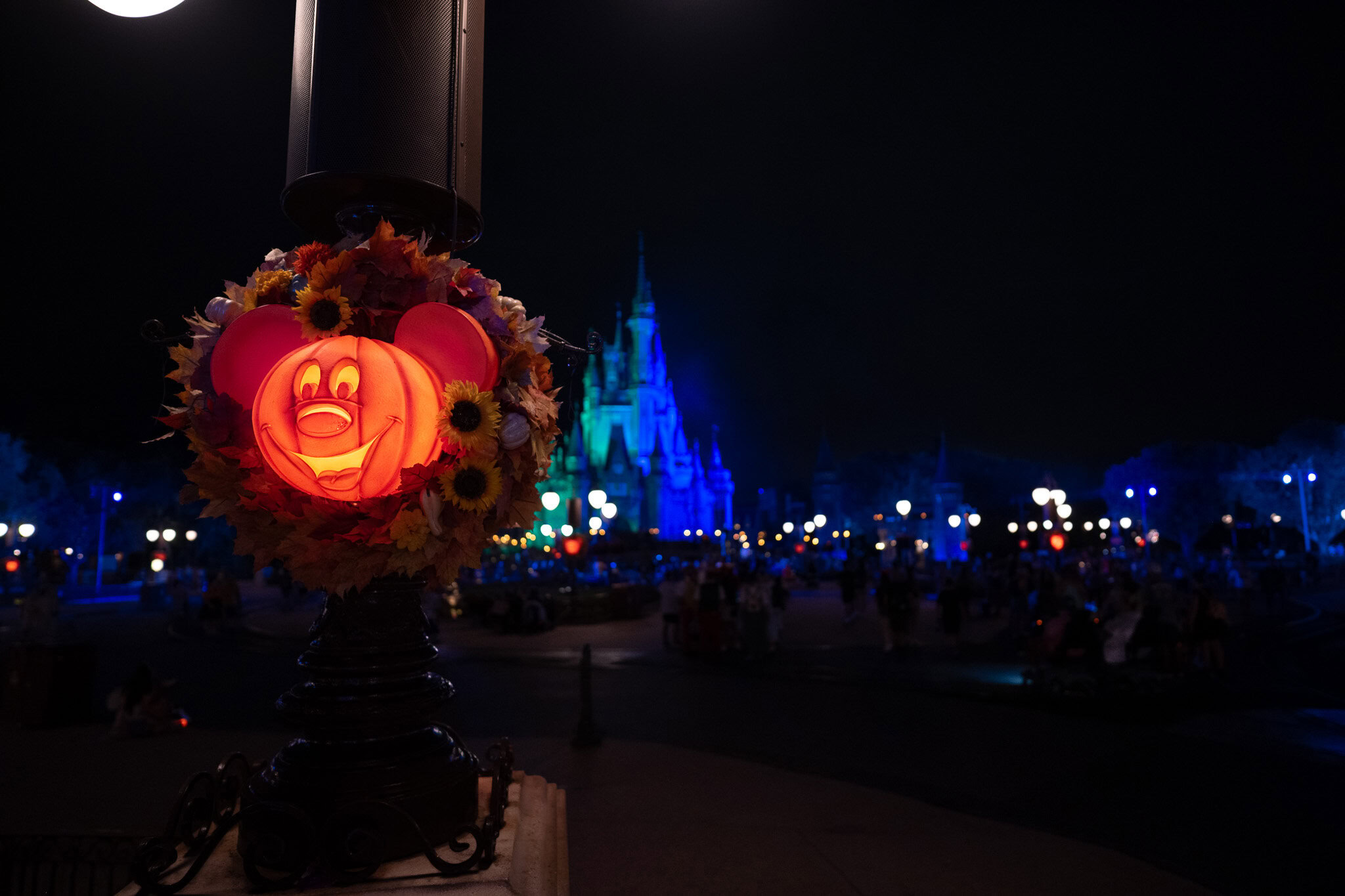 Mickey pumpkin Halloween wreath glowing near Cinderella Castle at night during MNSSHP