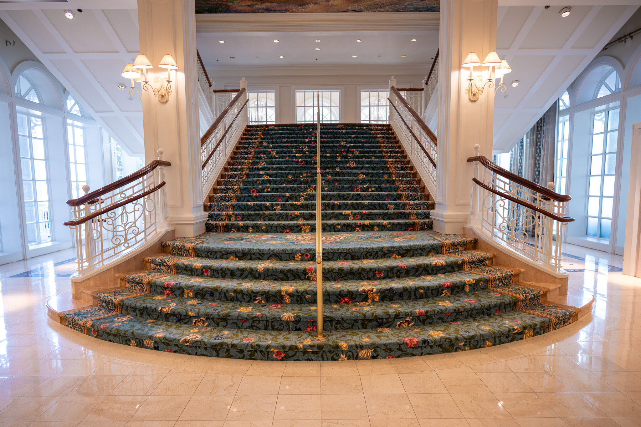 Grand staircase inside Disney’s Grand Floridian Resort Villas featuring floral carpet and elegant railings.