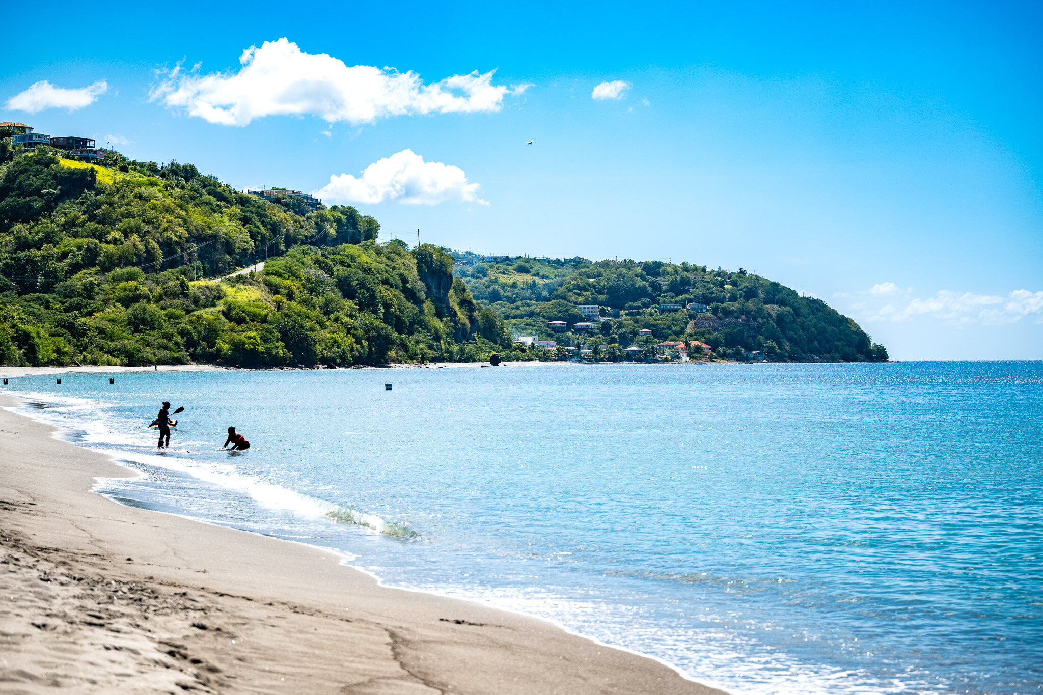 Wide view of Mero Beach in Dominica with calm water and people near shore