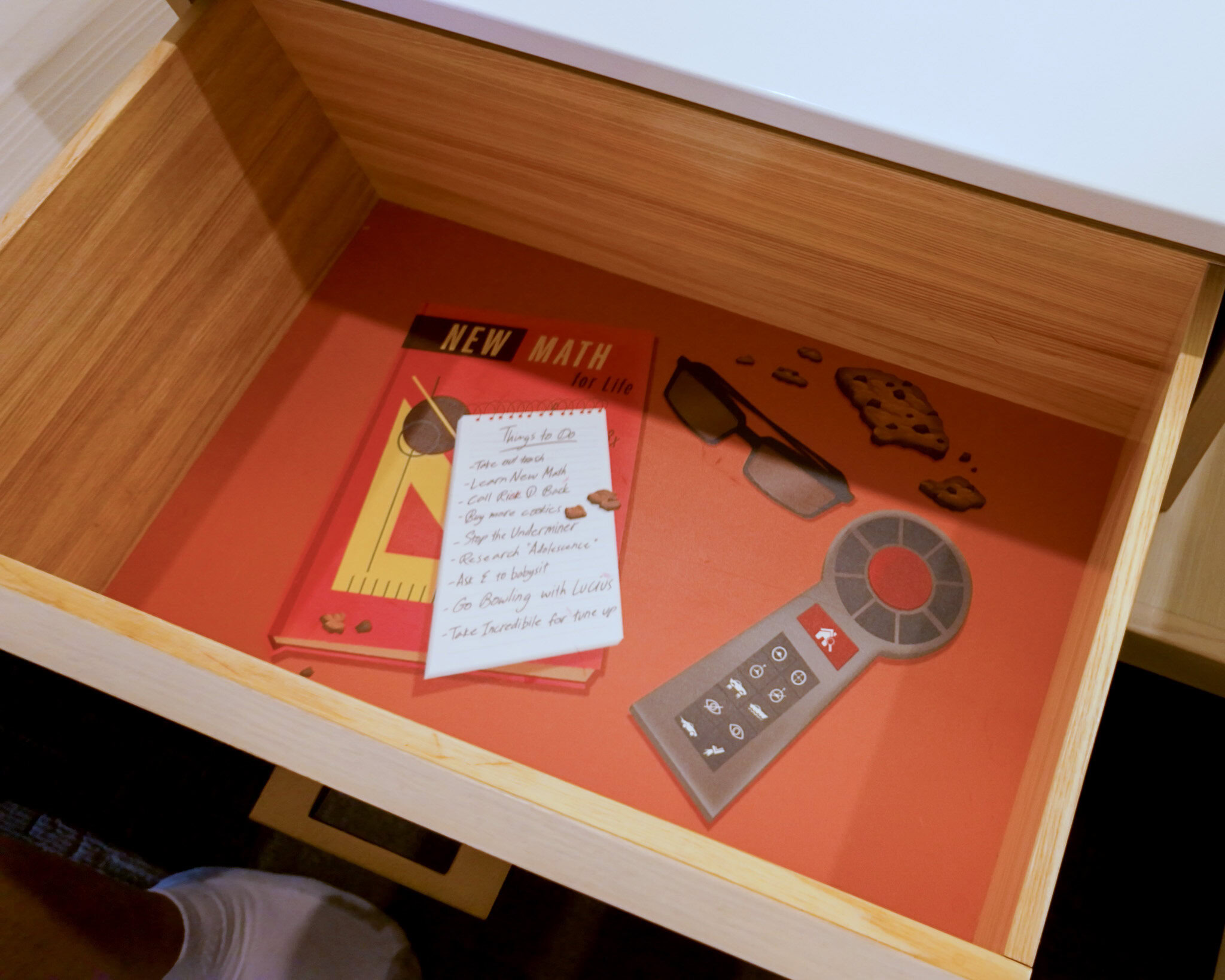 Open drawer in a Disney’s Contemporary Resort Garden Wing room showing a remote, themed materials, and visible debris.