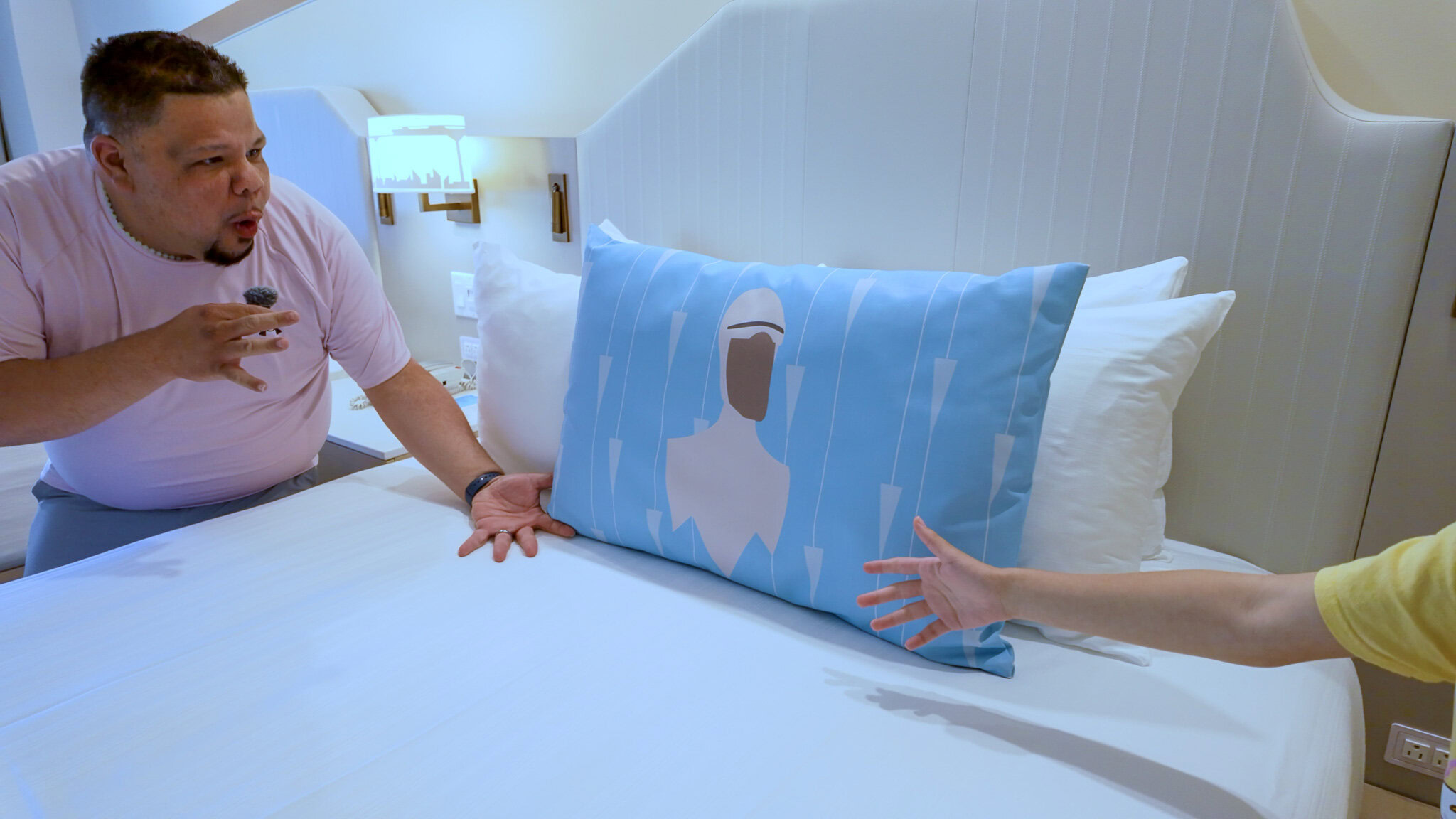 Guest pointing to an Incredibles-themed decorative pillow on a bed in a Disney’s Contemporary Resort Garden Wing room.
