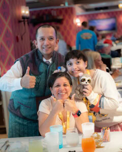 Disney Wish Arendelle Frozen Dinner server Daki smiling with family at dinner table.