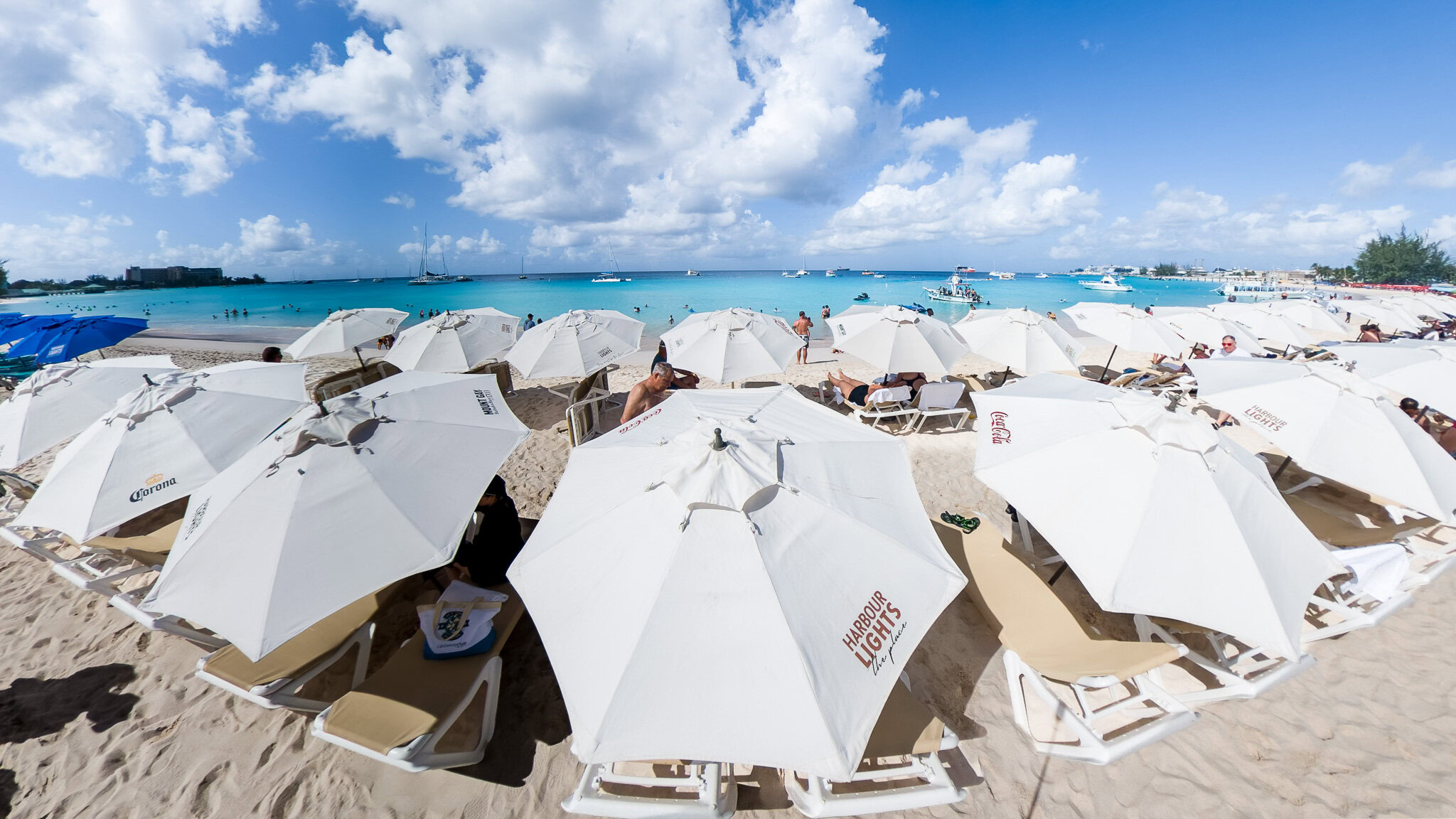 Panoramic view of Harbour Lights Beach with white umbrellas and turquoise water in Barbados.
