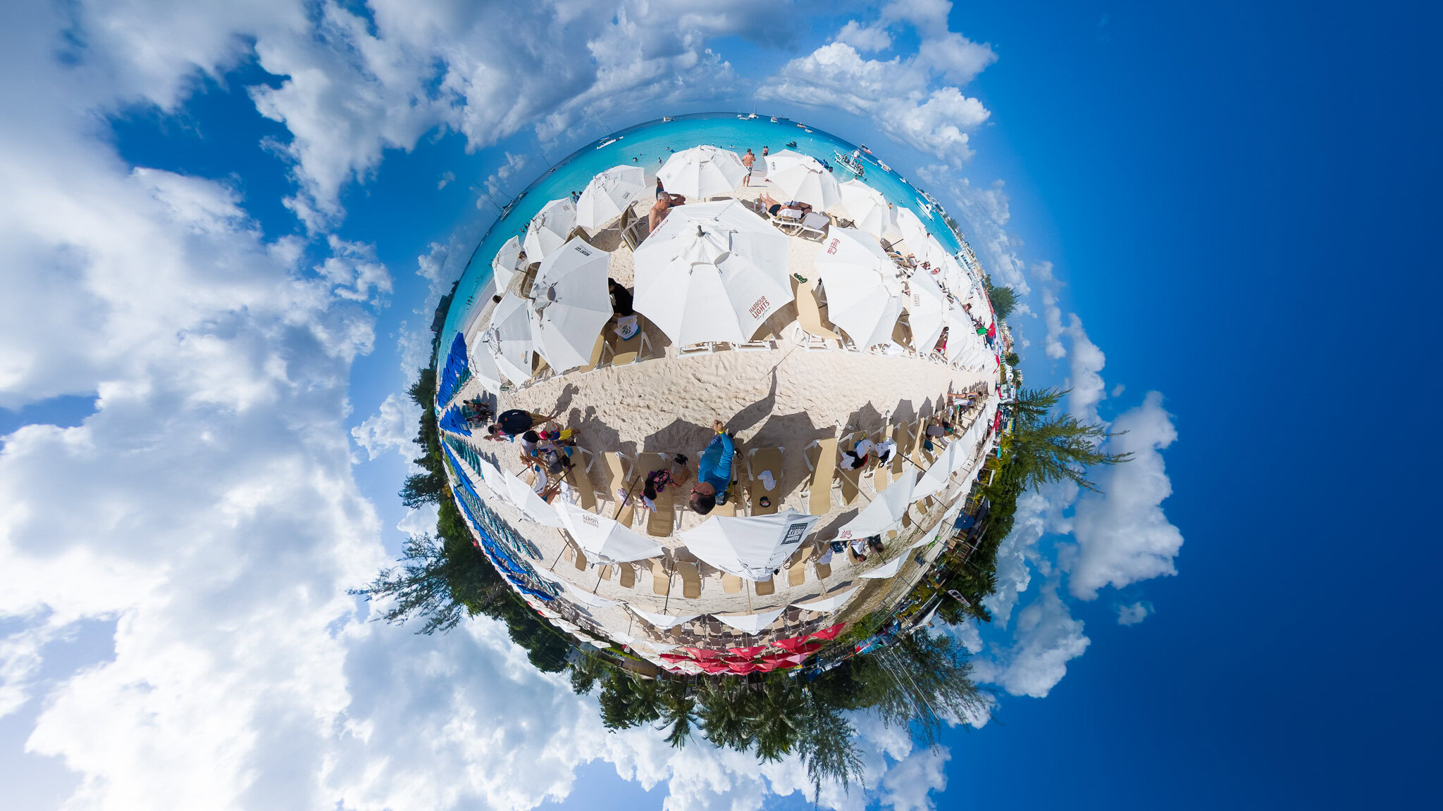 Tiny planet 360 view of Harbour Lights Beach with umbrellas and turquoise water in Barbados.