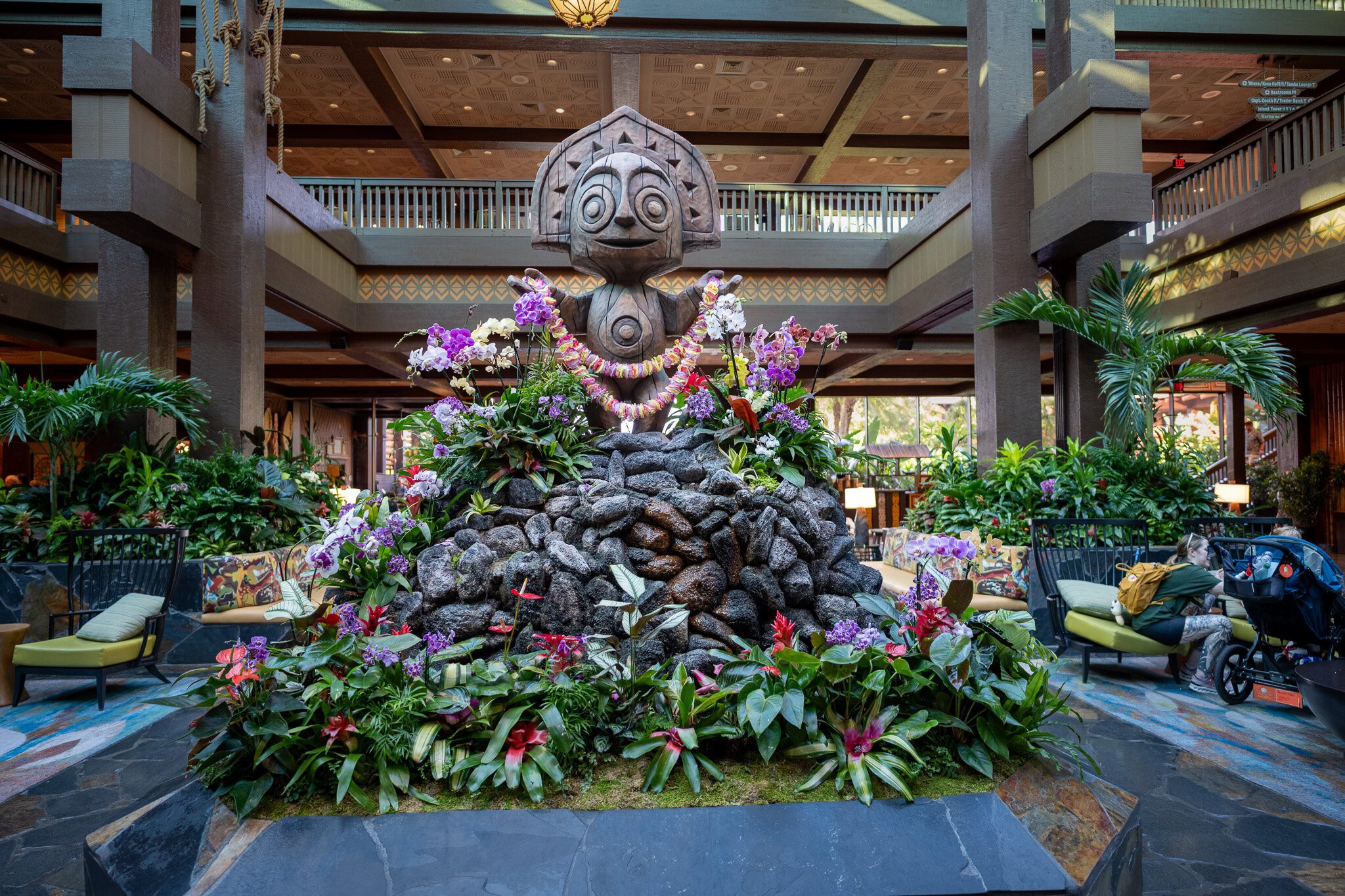 Tiki statue surrounded by tropical flowers in the lobby of Disney&rsquo;s Polynesian Village Resort