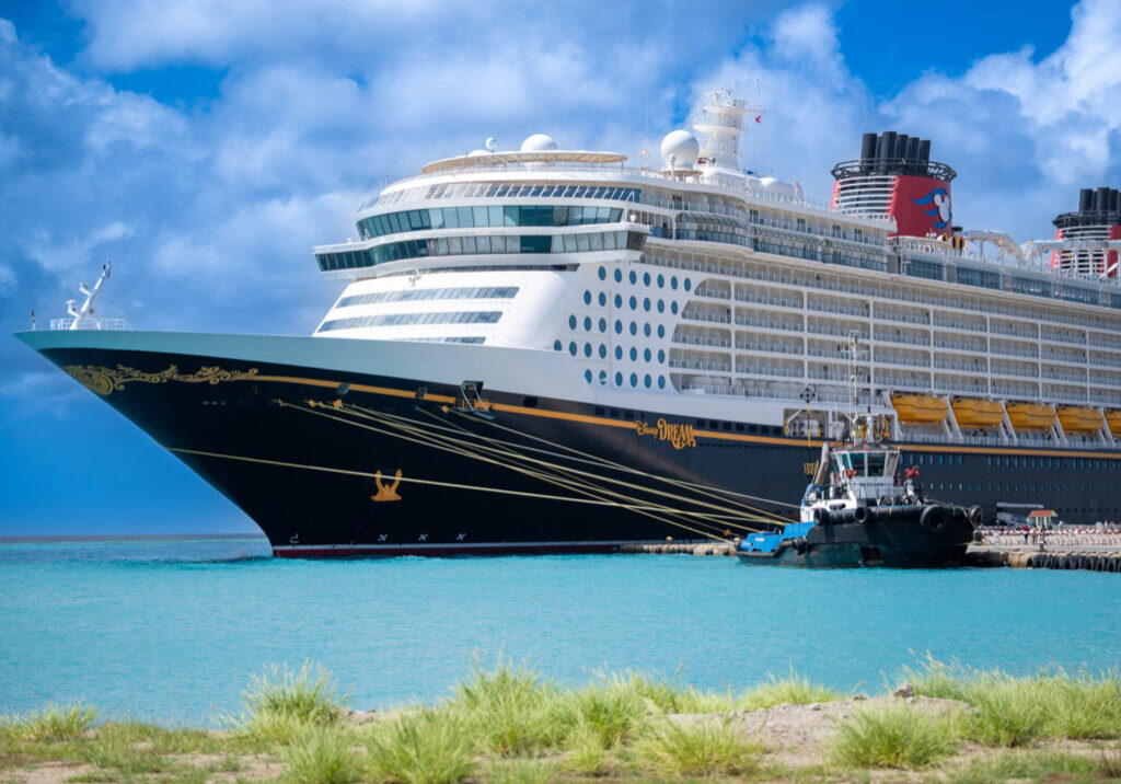 Disney Dream cruise ship docked at port in Aruba with a clear blue sky and turquoise waters.