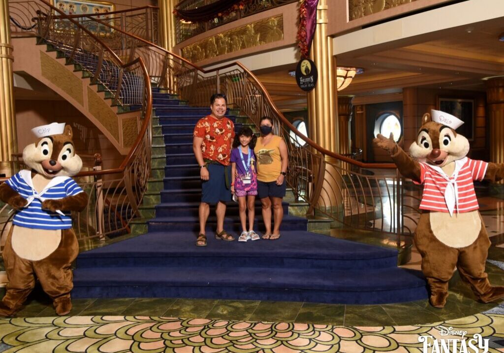 Daniela with her parents Raúl and Lucy posing with Chip and Dale on Disney Fantasy grand staircase