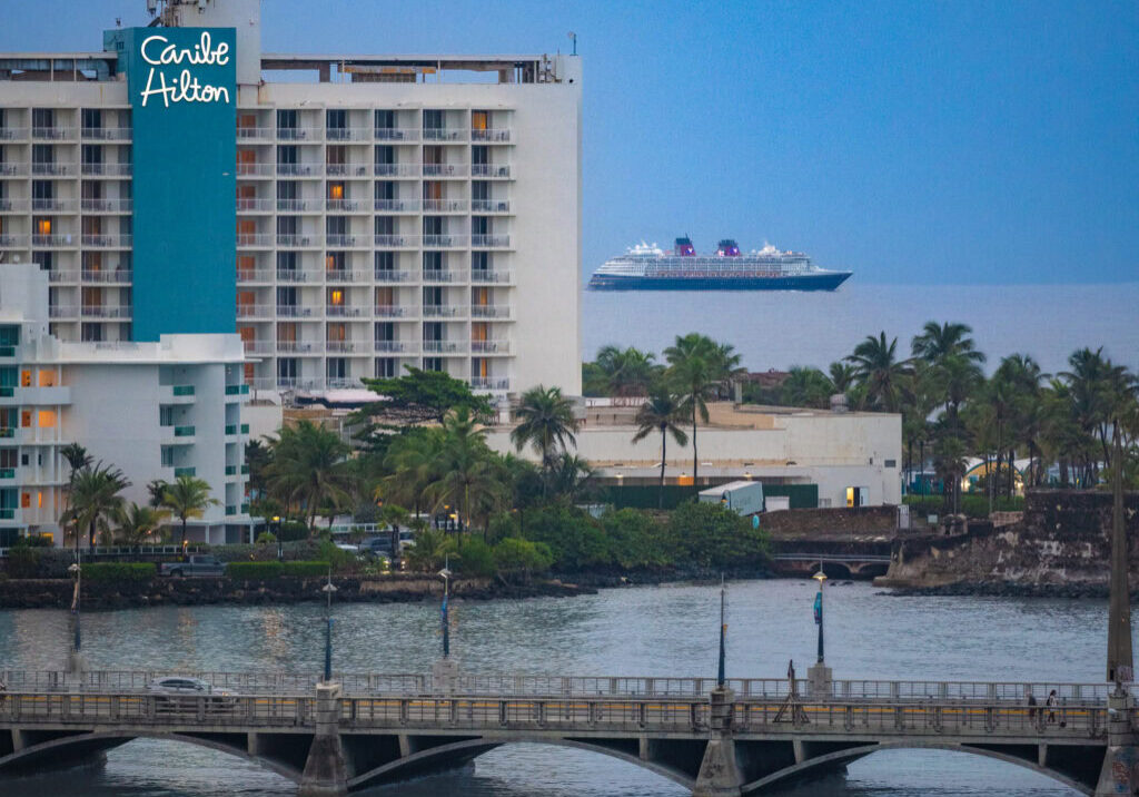 Disney Magic cruise ship sailing past Caribe Hilton along the San Juan waterfront in Puerto Rico.