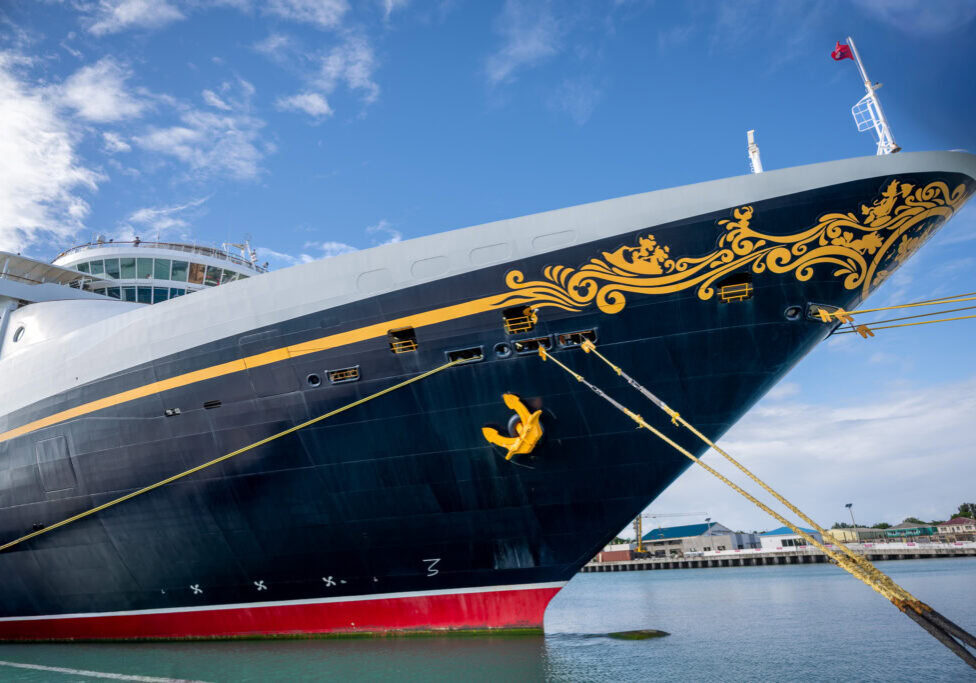Disney Magic cruise ship docked in St. John’s, Antigua, photographed from a low angle with clear blue skies.