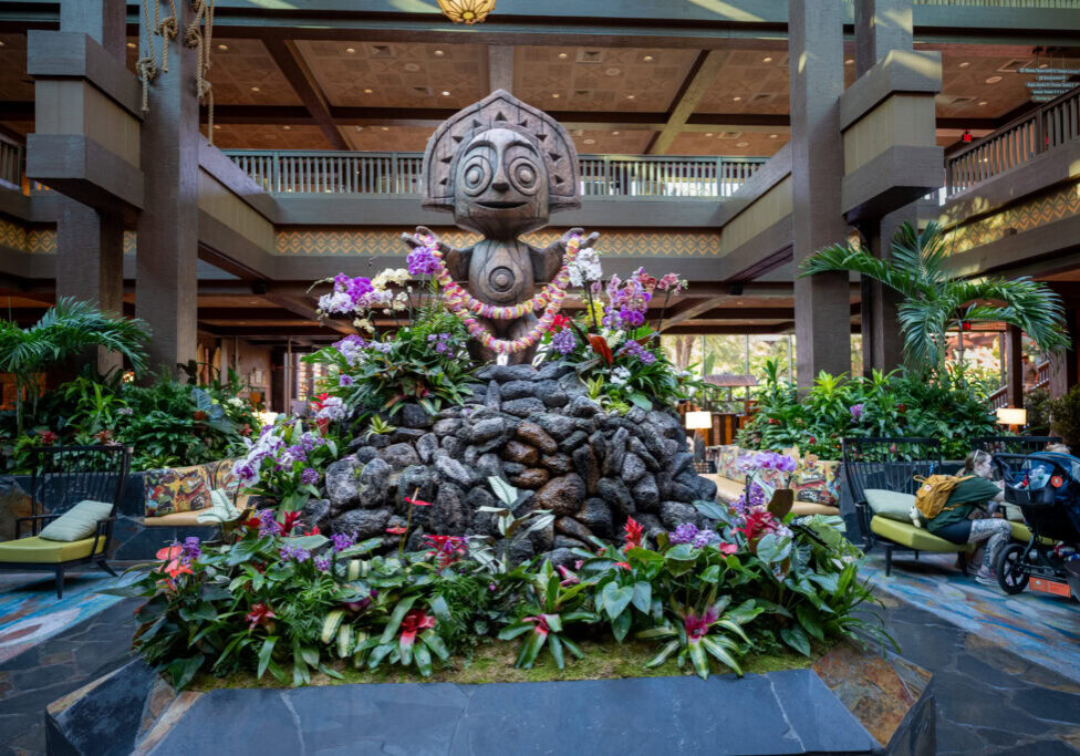 Tiki statue surrounded by tropical flowers in the lobby of Disney&rsquo;s Polynesian Village Resort