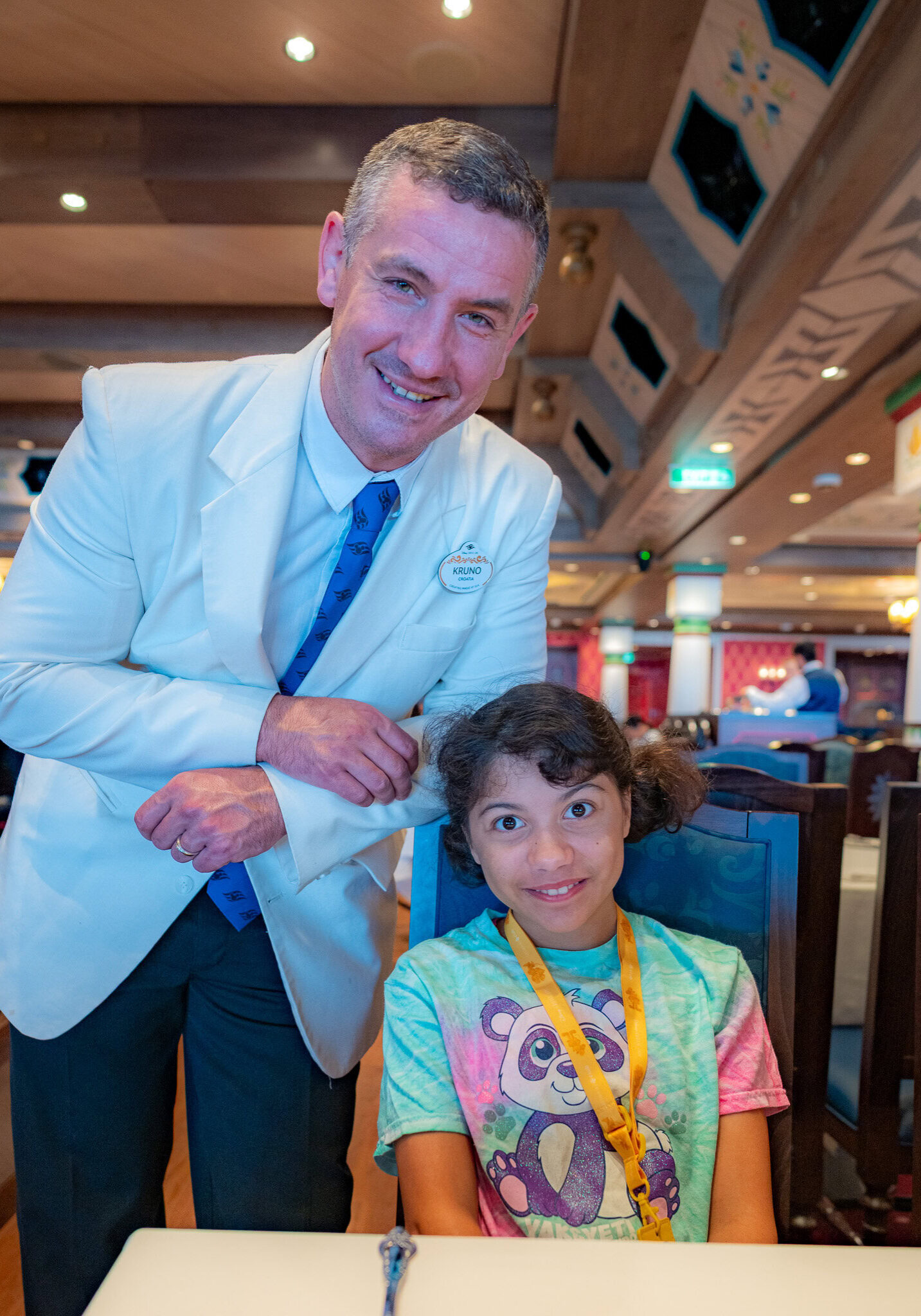 Kruno, a Disney Cruise Line head server, poses with Lucy at Arendelle restaurant.