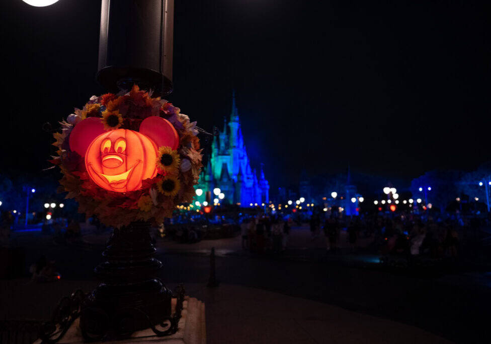 Mickey pumpkin Halloween wreath glowing near Cinderella Castle at night during MNSSHP